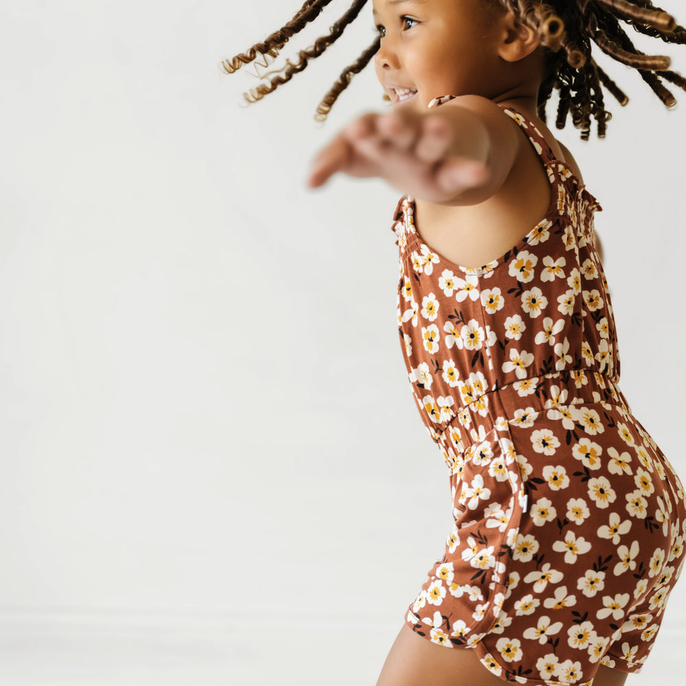 Child spinning around wearing a Mocha Blossom printed smocked romper