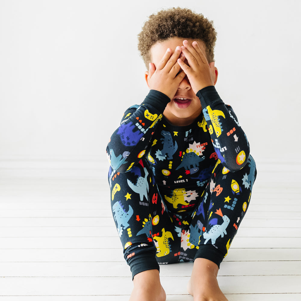 Child sitting wearing Next Level Dinos two piece pajama set