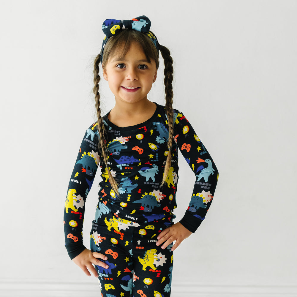 Child wearing a Next Level Dinos luxe bow headband paired with matching Next Level Dinos two piece pajama set