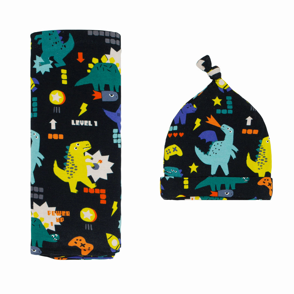 Flat lay image of a Next Level Dinos swaddle and hat set