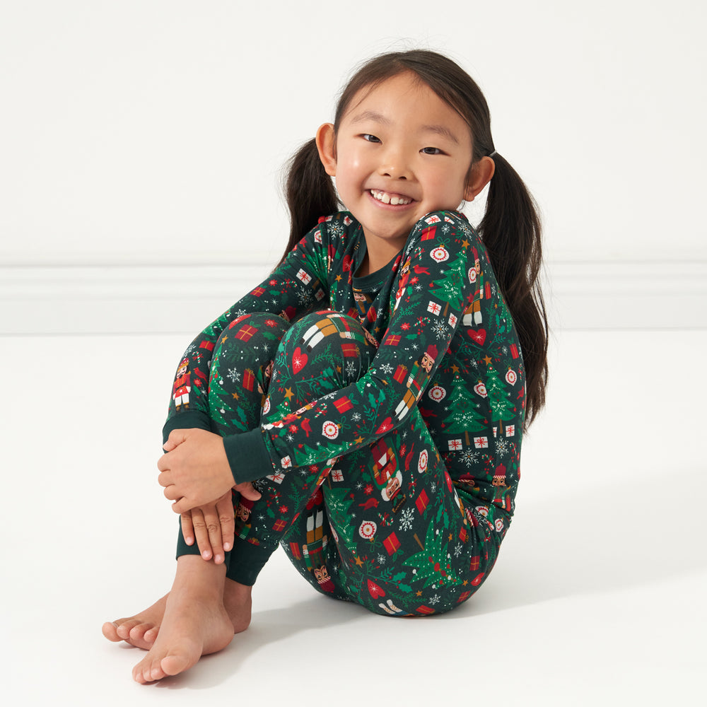 Child sitting and posing wearing a Night at the Nutcracker two piece pajama set