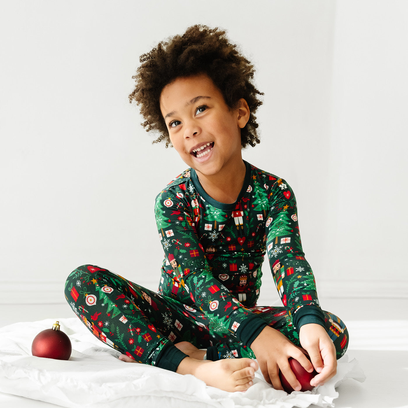 Child sitting and posing wearing a Night at the Nutcracker two piece pajama set