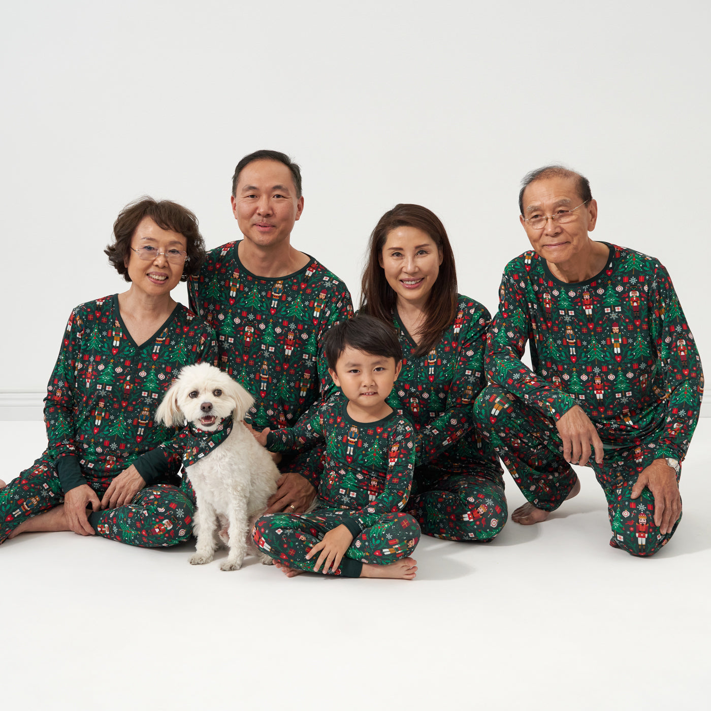 Family of five and their dog wearing matching Night at the Nutcracker Pajama sets. Mom and Grandma are wearing women's Night at the Nutcracker women's pajama tops and matching women's pajama bottoms. Dad and Grandpa are wearing Night at the Nutcracker men's pajama top and matching pajama bottoms. Child is wearing a Night at the Nutcracker two piece pajama set. Their dog is wearing a Night at the Nutcracker pet bandana