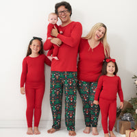 Family of Five. Dad is wearing Night at the Nutcracker men's pajama bottoms paired with a Holiday Red men's long sleeve pajama top. Mom is wearing Night at the Nutcracker women's pajama bottoms paired with a Holiday Red long sleeve pajama top. Daughters are wearing Holiday Red pajamas in two piece and zippy styles paired with Night at the Nutcracker and Holiday Red luxe bow headbands