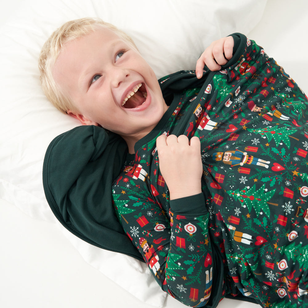 Child laying on a bed wrapped in a Night at the Nutcracker large cloud blanket. Child is wearing a matching Night at the Nutcracker two piece pajama set