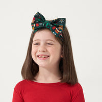 Alternate close up image of a child wearing a Night at the Nutcracker luxe bow headband with a Holiday Red two piece pajama set