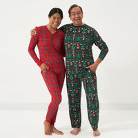 Man and a woman posing together wearing coordinating pajamas. Woman is wearing Holiday Plaid women's pajama top and matching women's pajama bottoms. Man is wearing Night at the Nutcracker men's pajama top and matching pajama bottoms.
