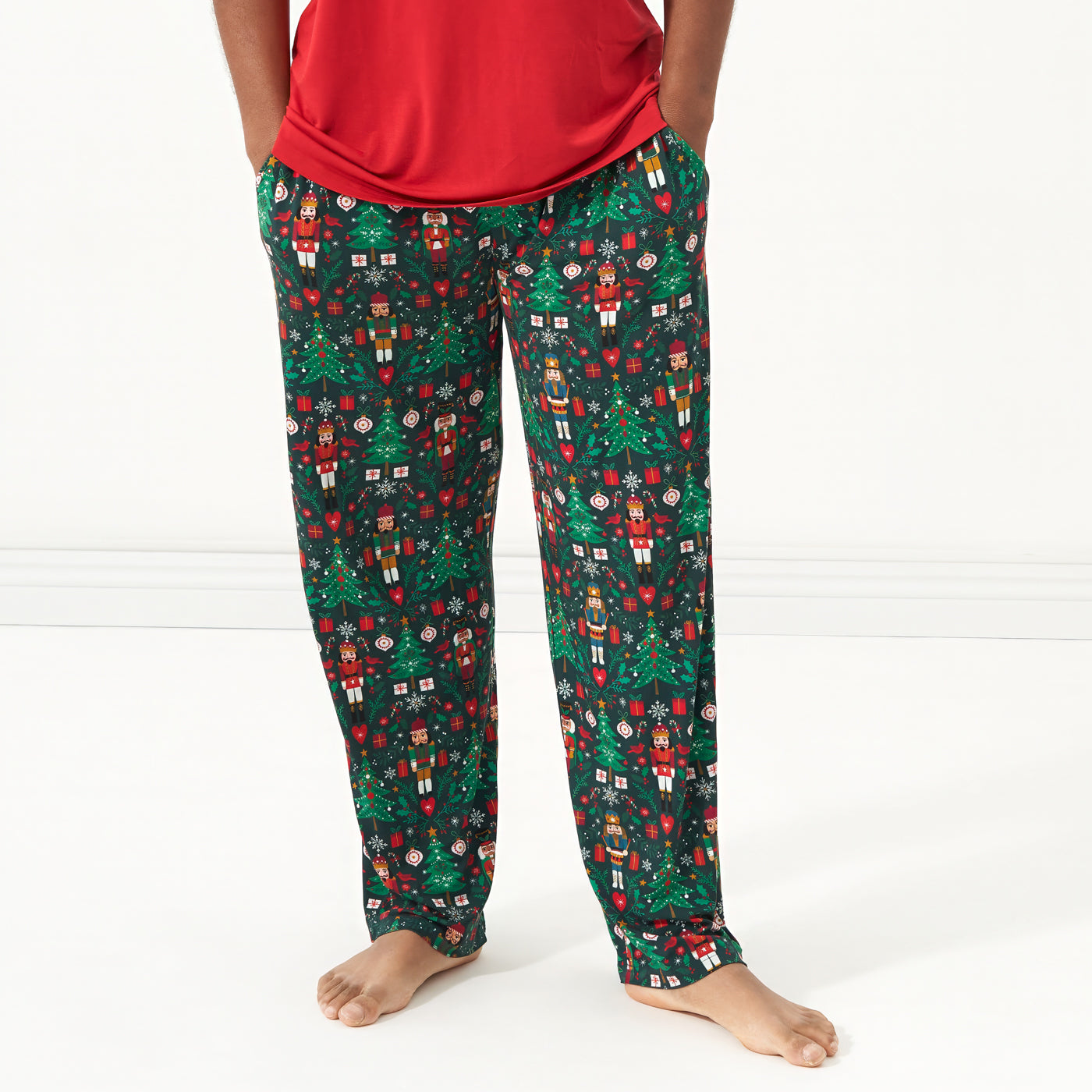 Close up image of a man wearing men's Night at the Nutcracker printed pajama bottoms paired with a Holiday Red men's pajama top