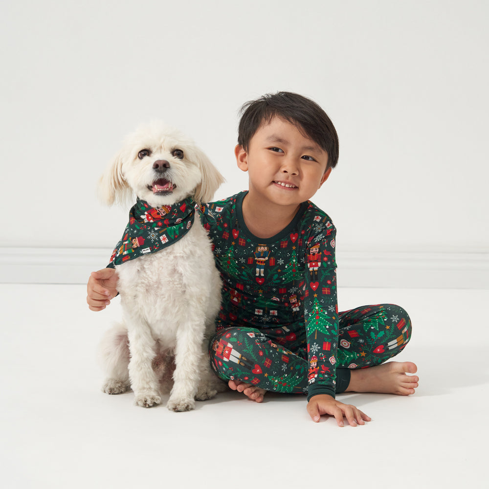 Child posing with their dog. Child is wearing a Night at the Nutcracker two piece pajama set matching their dog wearing a Night at the Nutcracker printed pet bandana 
