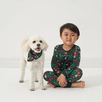 Alternate image of a child posing with their dog. Child is wearing a Night at the Nutcracker two piece pajama set matching their dog wearing a Night at the Nutcracker printed pet bandana