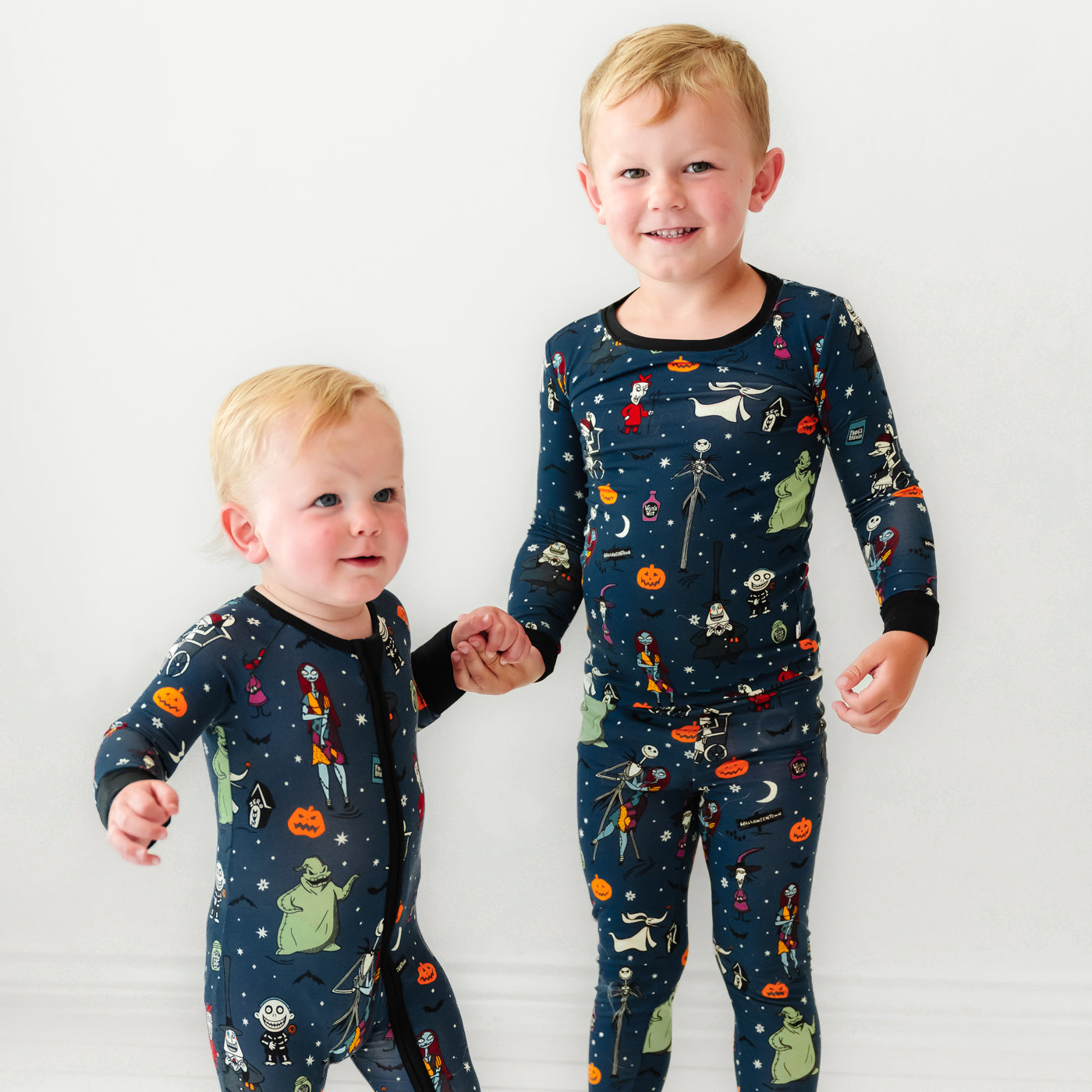 Two children holding hands wearing matching Jack Skellington and Friends printed pajamas