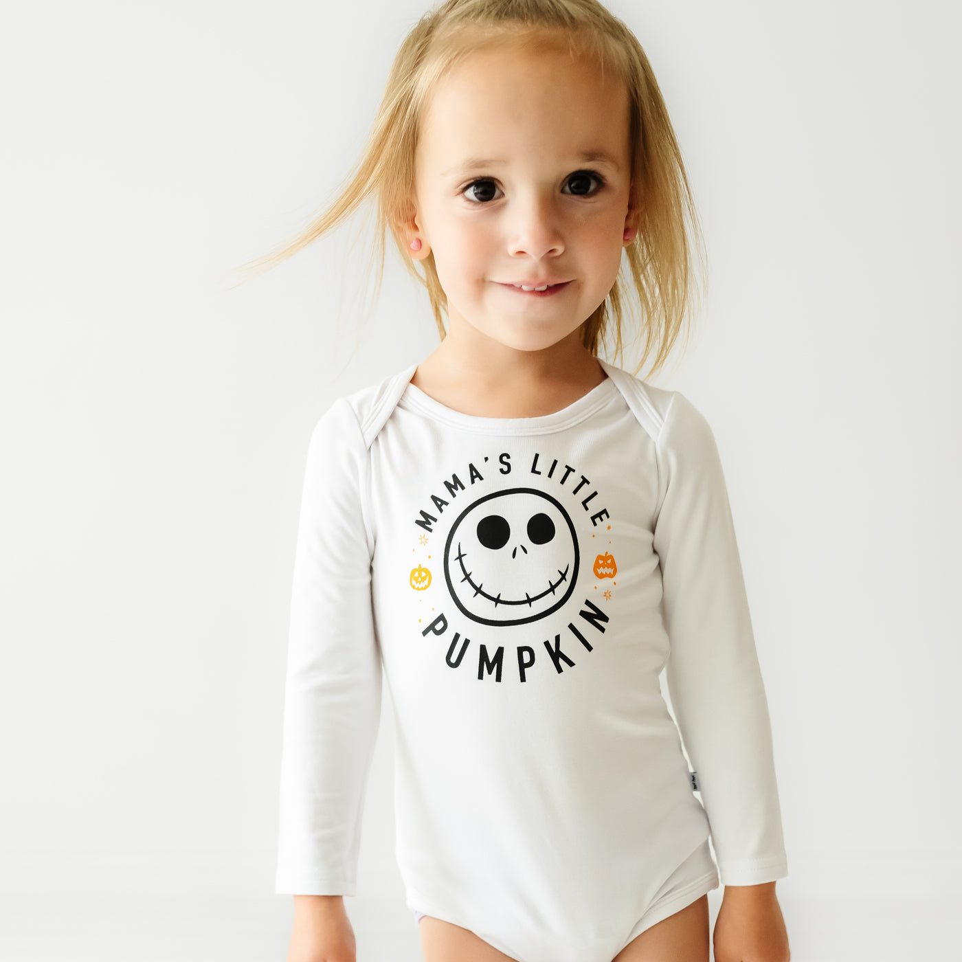 Child wearing a Mama's Little Pumpkin graphic bodysuit