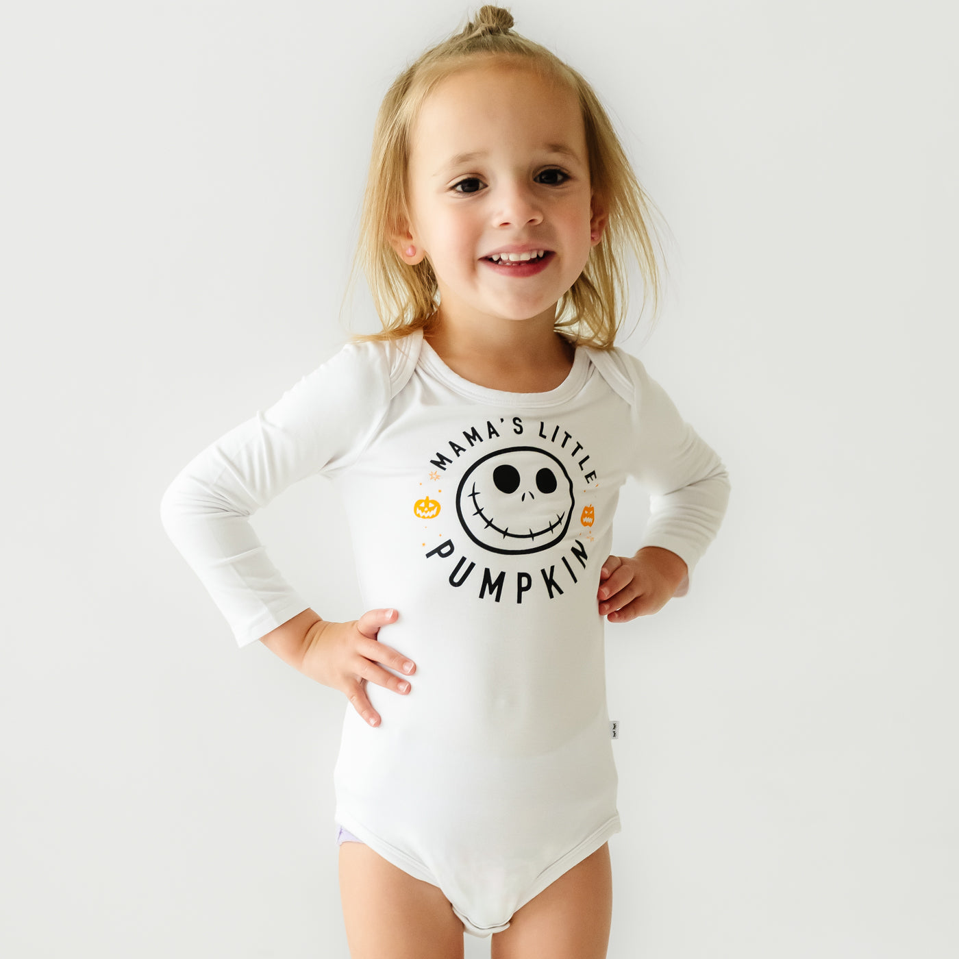 Child standing with their hands on their hips wearing a Mama's Little Pumpkin graphic bodysuit