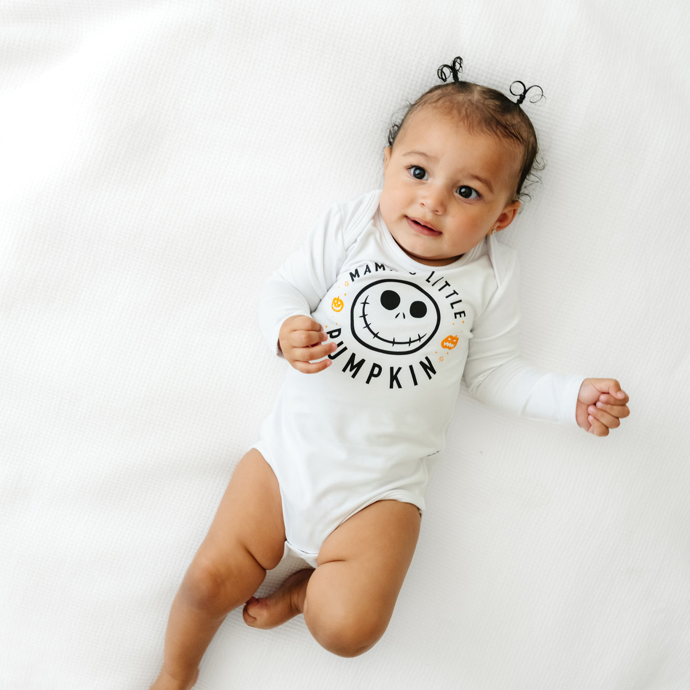 Alternate image of a child laying on a bed wearing a Mama's Little Pumpkin graphic bodysuit