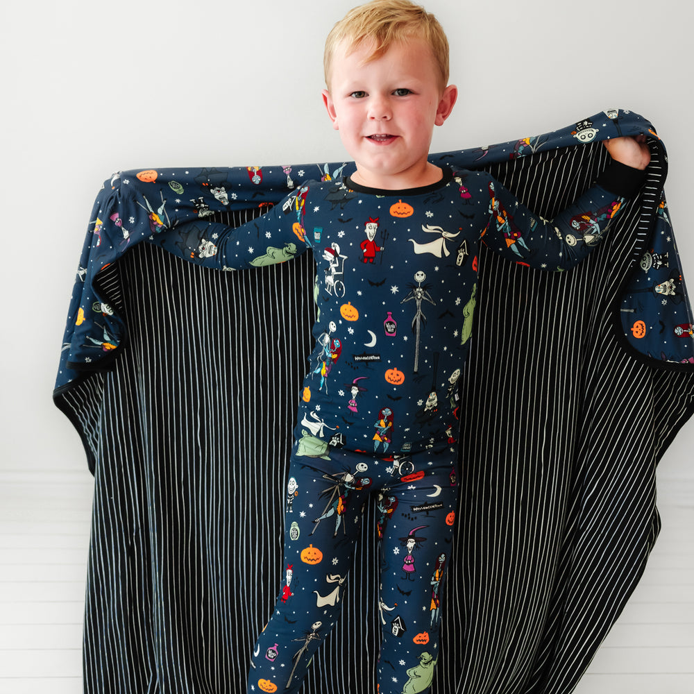 Child with a Jack Skellington and Friends printed large cloud blanket around their shoulders, showing the striped backing