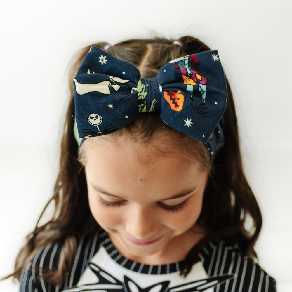 Close up image of a child wearing a Jack Skellington and Friends printed luxe bow headband