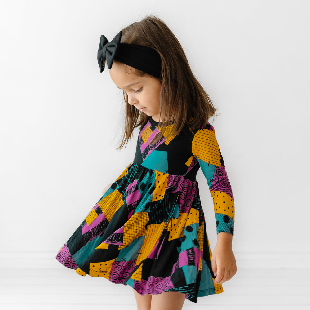 Child spinning around wearing a Sally's Patchwork twirl dress with bodysuit