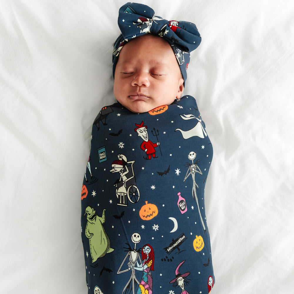 Child laying on a blanket in a Jack Skellington and Friends printed swaddle and luxe bow headband set