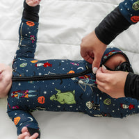 Close up image of a child laying on a bed wearing a Jack Skellington and Friends printed zippy with a parent zipping it closed