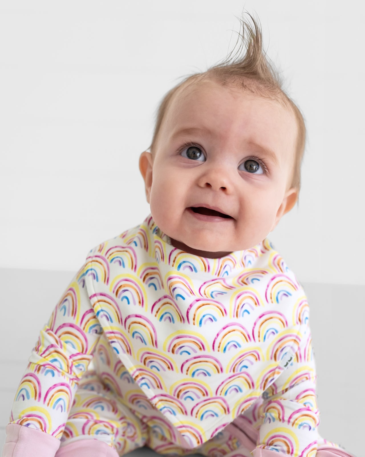 Close up of a child wearing a Pastel Rainbows baby bandana bib