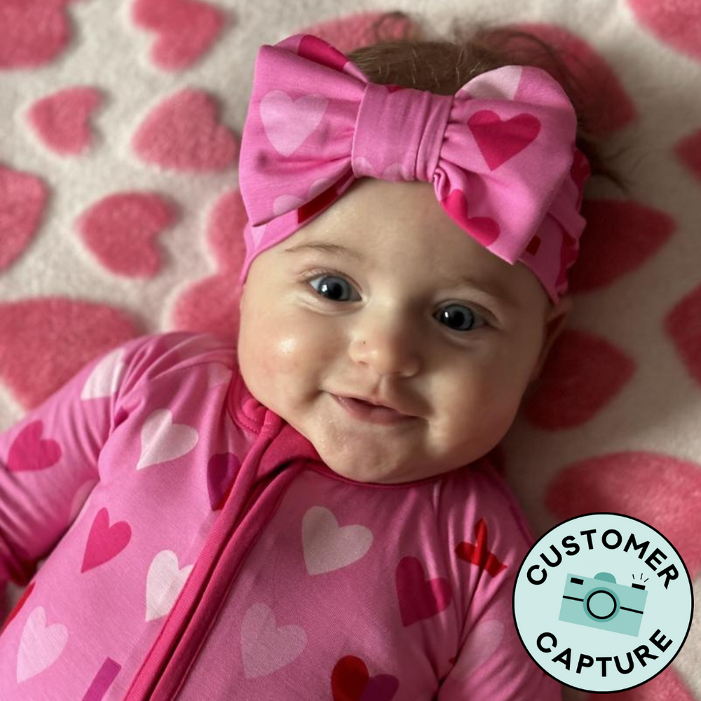 Click to see full screen - Customer Capture image of a child wearing a pink xoxo luxe bow headband and matching zippy