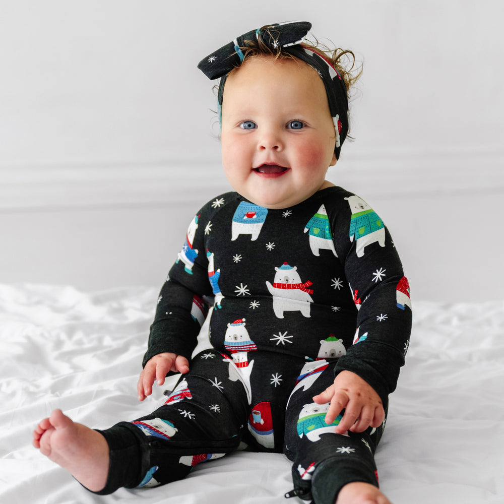 Click to see full screen - Child sitting wearing a Polar Bear Pals crescent zippy paired with a matching luxe bow headband