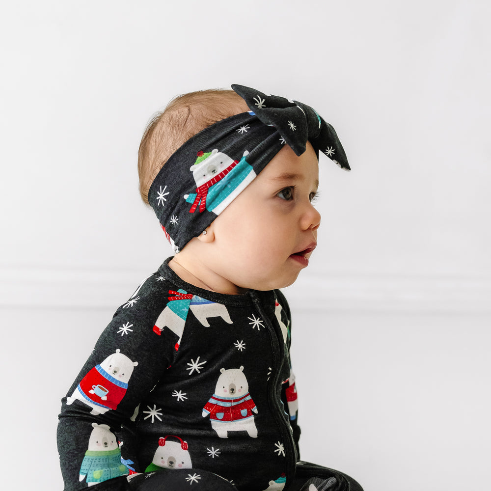 Click to see full screen - profile view of a child wearing a Polar Bear Pals luxe bow headband paired with  a matching zippy