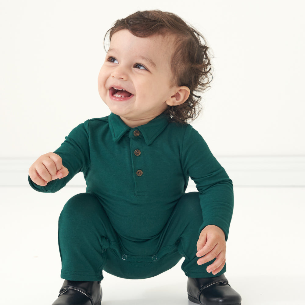 Child squatting wearing an Emerald polo romper