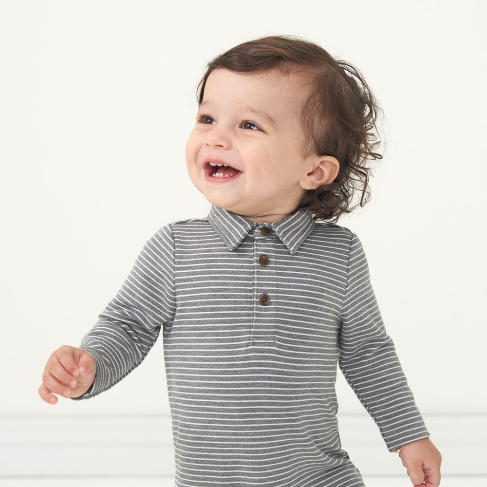 Close up image of a child posing wearing a Heather Charcoal Stripes polo romper