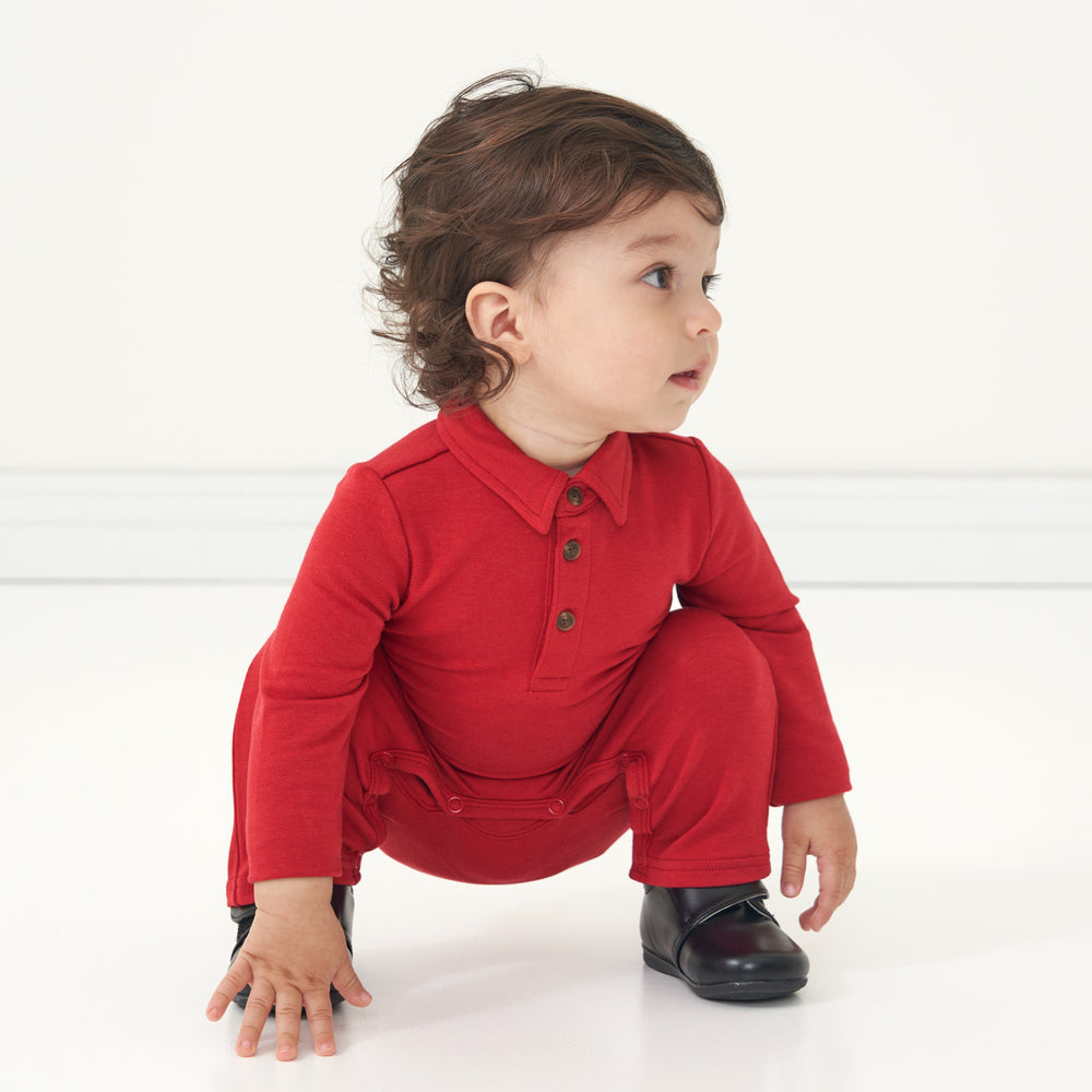 Child squatting wearing a Holiday Red polo romper