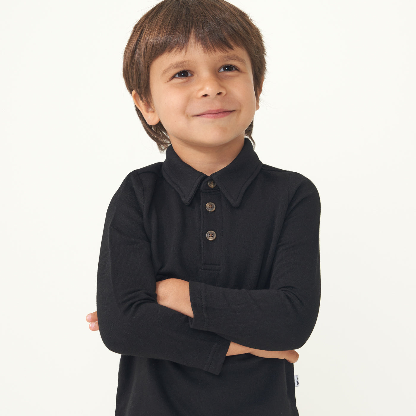 Child wearing a Black polo shirt with their arms crossed