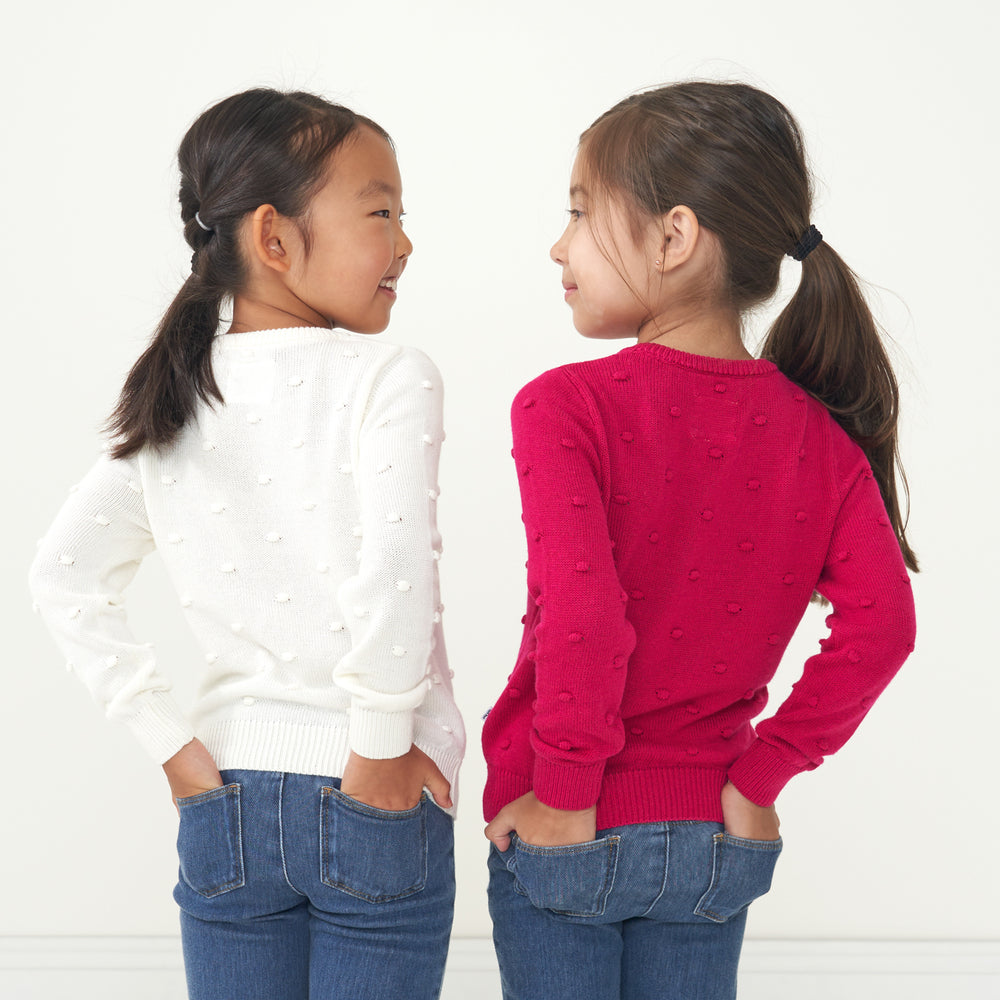 two children coordinating in Ivory and Mixed Berry Pom Pom sweaters