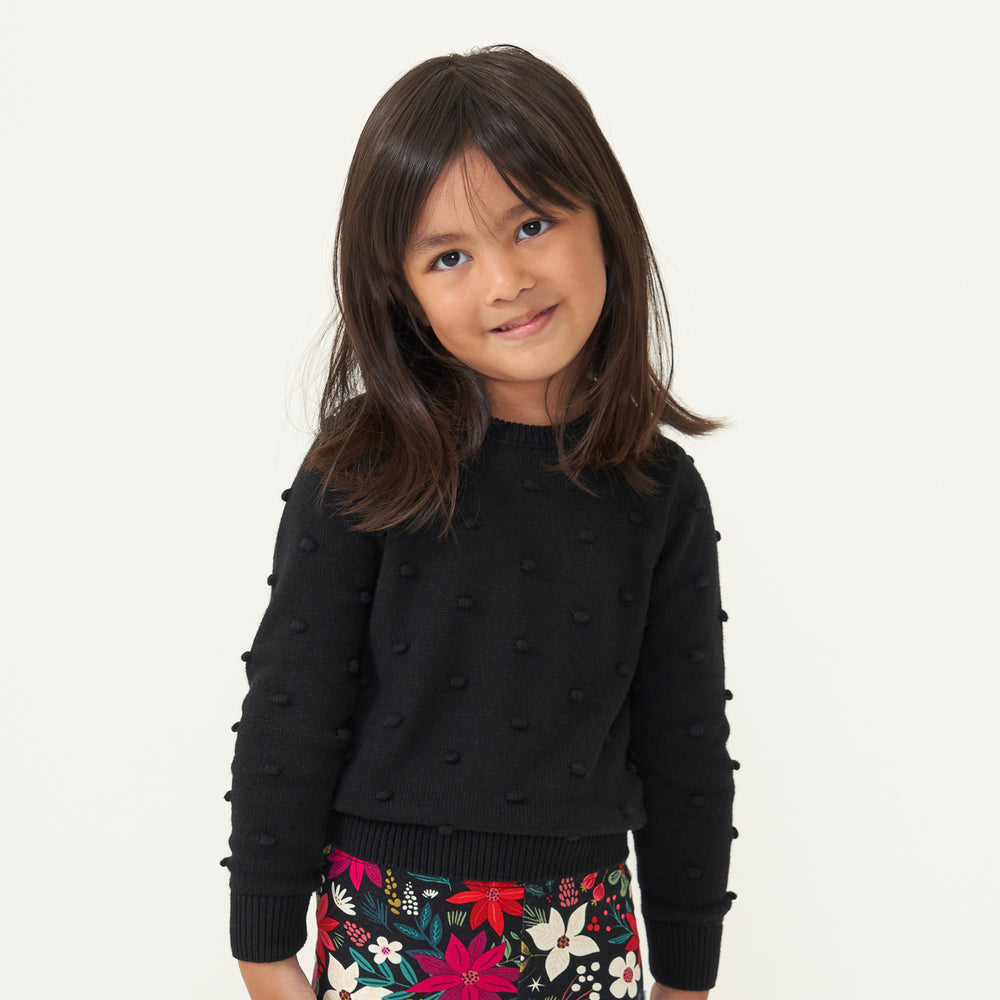 Child wearing a Black pom pom sweater and coordinating Berry Merry leggings