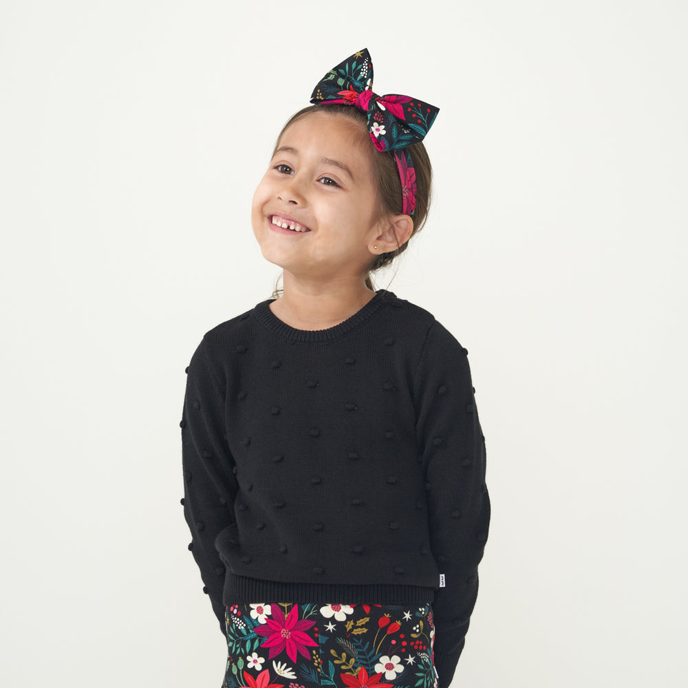 Child wearing a Black pom pom sweater and coordinating Berry Merry luxe bow headband and leggings