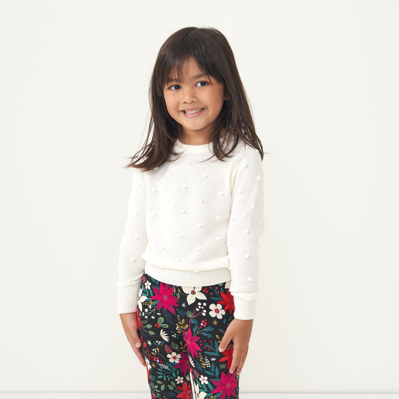 Child wearing an Ivory pom pom sweater and coordinating Berry Merry leggings