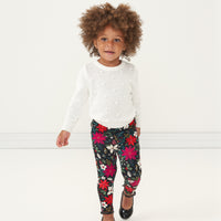 Child walking wearing an Ivory pom pom sweater and coordinating Berry Merry leggings