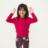 Child posing wearing a Mixed Berry Pom Pom sweater paired with Berry Merry leggings