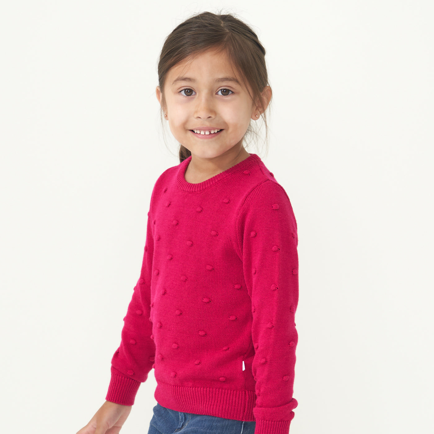 profile view of a child wearing a Mixed Berry Pom Pom sweater