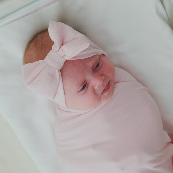 Newborn swaddled in the Prima Pink Ribbed Swaddle & Luxe Bow Headband Set