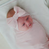 Newborn swaddled in the Prima Pink Ribbed Swaddle & Luxe Bow Headband Set