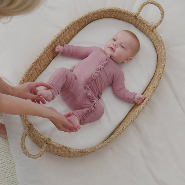 baby laying in a bassinet wearing a Rosewood Ruffle Zippy