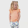 Video of children wearing a pair of Seas the Day dolphin shorts paired with a Navy Peplum top and a Peach Nectar flutter tee