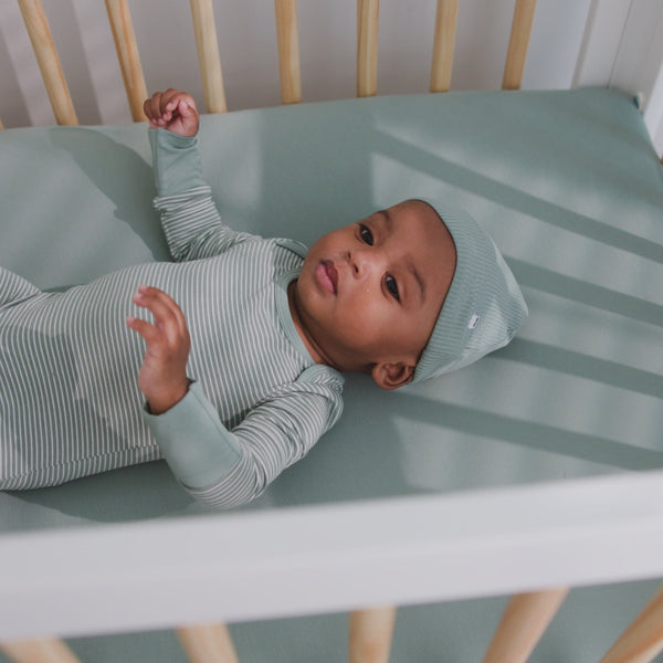 Newborn laying in a crib with the Willow Mini Crib Sheet