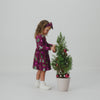 Girl wearing the Cranberry Tree Traffic Bow Back Skater Dress putting ornaments on a Christmas tree