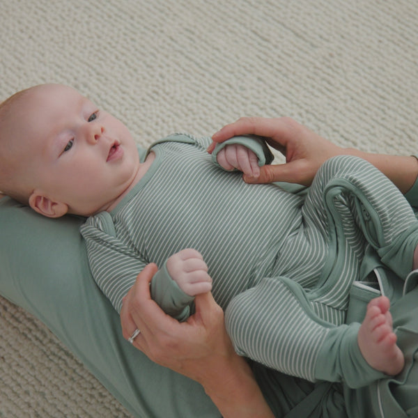 Newborn laying in their parent's lap, wearing a Willow Stripes Lap Shoulder Zippy