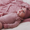 Newborn wearing the Rosewood Stripe Flutter Bodysuit laying on a matching baby blanket