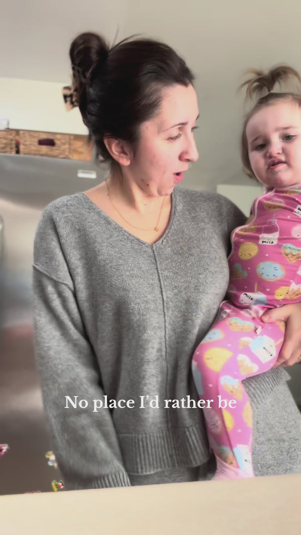 Child being held by their mother, wearing a Pink Cookies & Milk Zippy