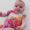 Video of an infant laying on a blanket wearing a Rainbow Blooms Flutter Bodysuit