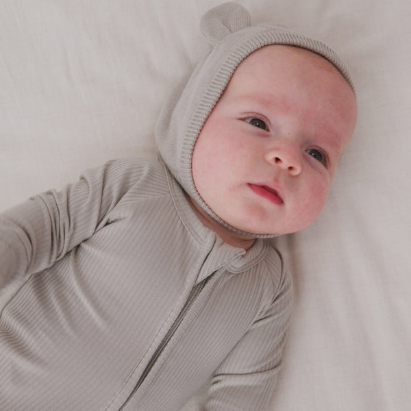 Newborn wearing the Dove Gray Bear Bonnet with a matching gray zipper pajama