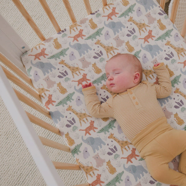 Newborn laying in a crib wearing the Sweet Safari Mini Crib Sheet